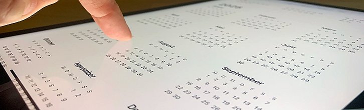 Finger tippt auf einem Tablet auf einen Kalender